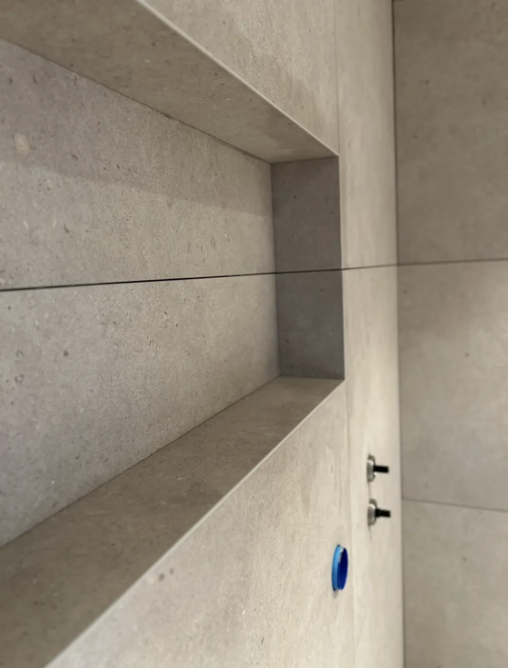 Gerad nisch med epoxyfog för en exakt och hållbar badrumslösning utförd av Mplattsättning AB.