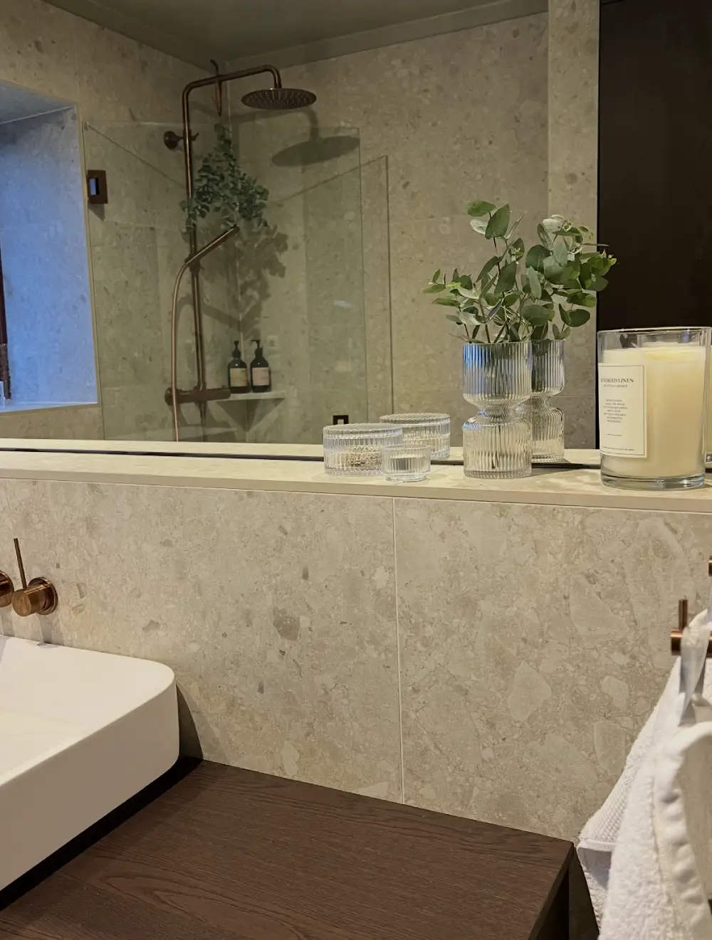 Detaljbild på stilrent och harmoniskt badrum med samma platta på golv och vägg för ett enhetligt och mysigt intryck, utfört av Mplattsättning AB.