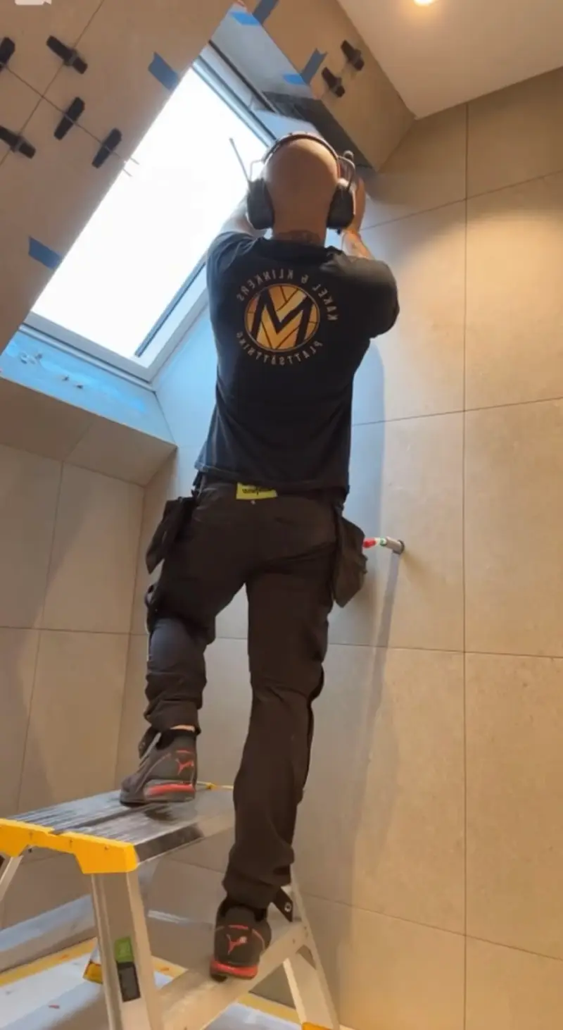 Plattsättaren Jonathan i arbete med att montera kakel runt ett takfönster, utfört av Mplattsättning AB.