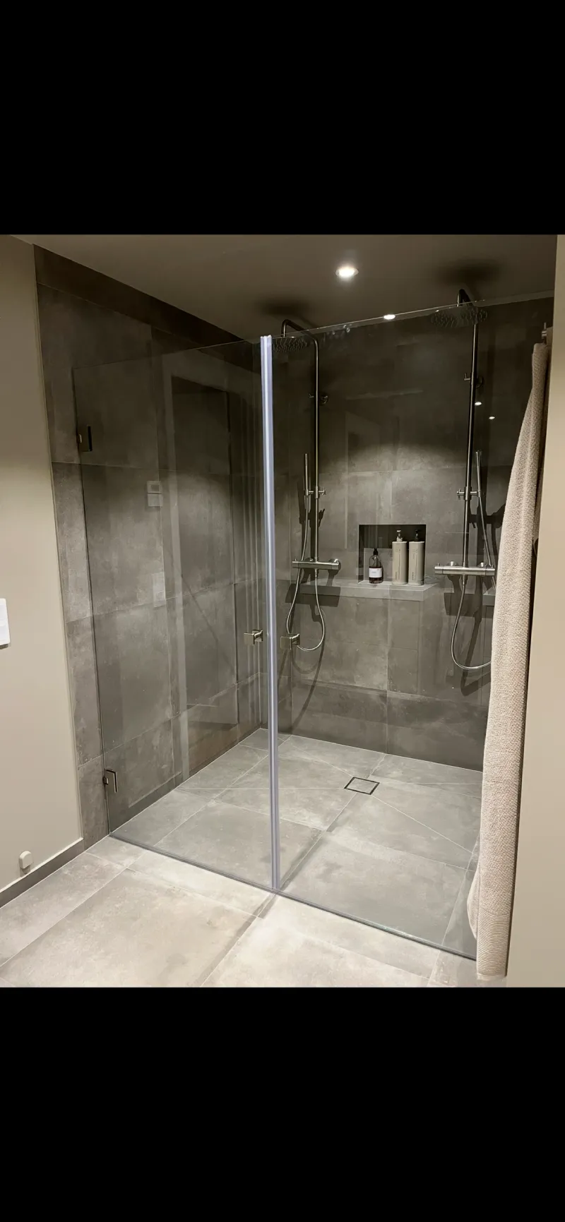 Stor dusch med smidig nisch, stora grå plattor på både golv och vägg, plattsättning av Mplattsättning AB.