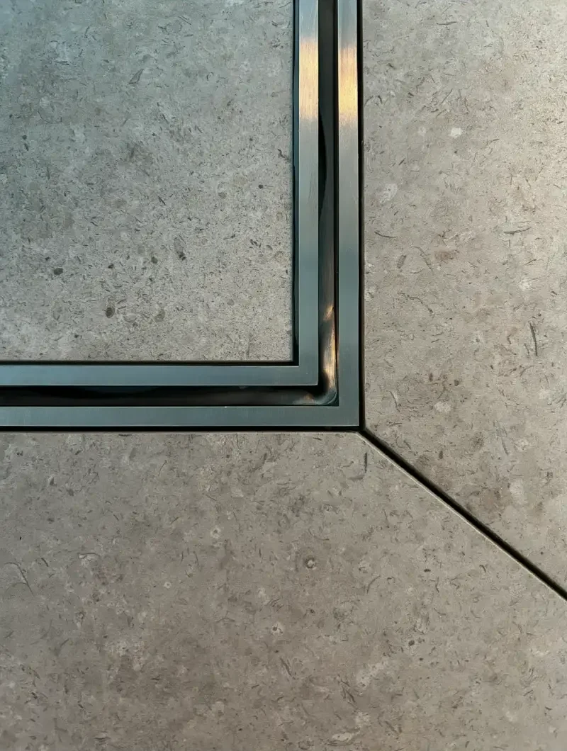 Närbild på tile-in-brunn integrerad i golvet, monterad av Mplattsättning AB.