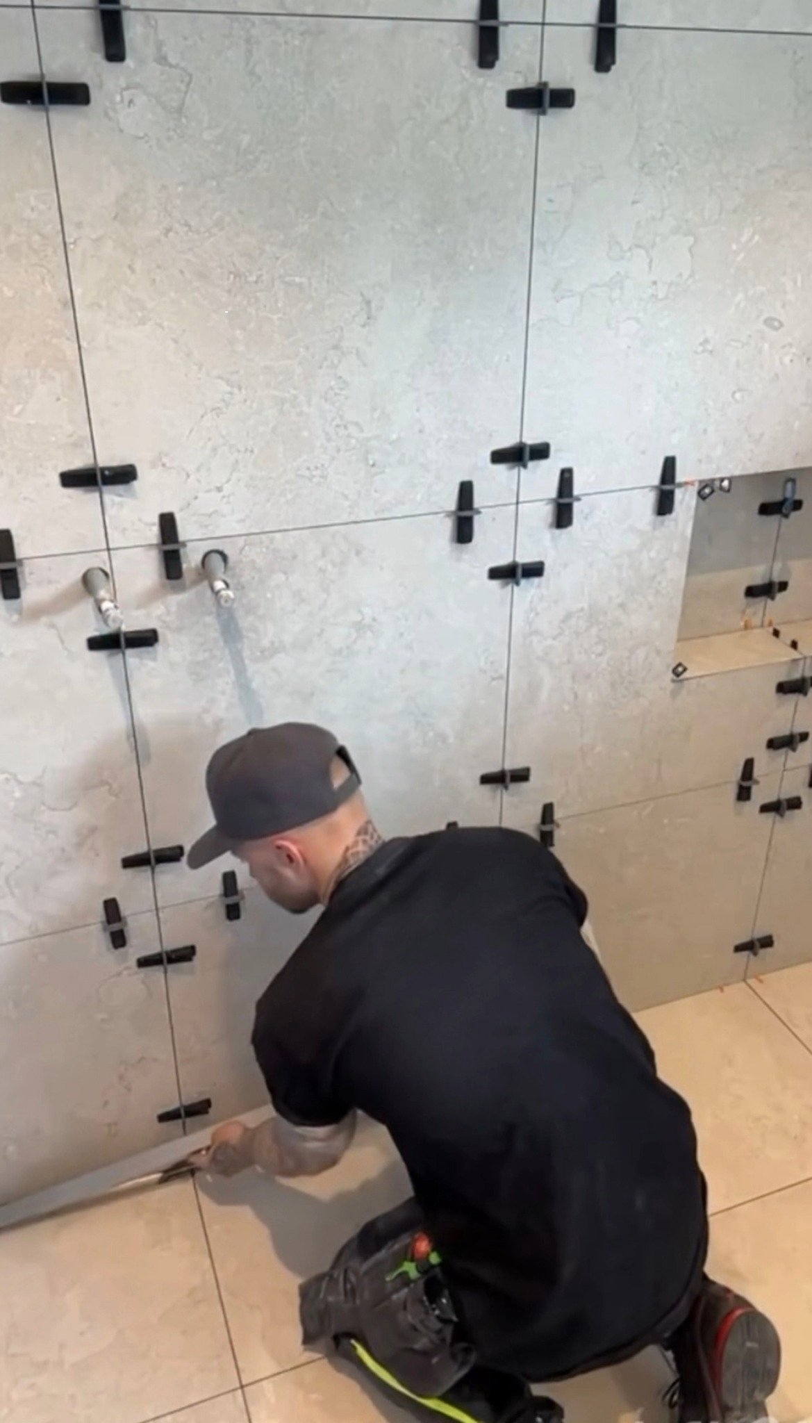 Plattsättare integrerar tile-in-brunn i kaklat golv för en sömlös och stilren badrumslösning. Arbetet utförs av Mplattsättning AB.