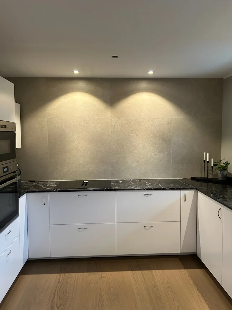 Kök med granitbänkskiva och storformatsplattor på väggen, plattsättning av Mplattsättning AB.